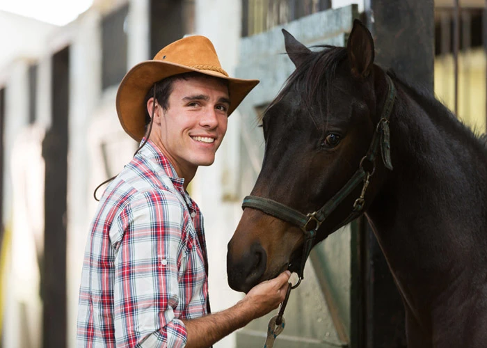 Cow-boy avec un cheval dans une écurie