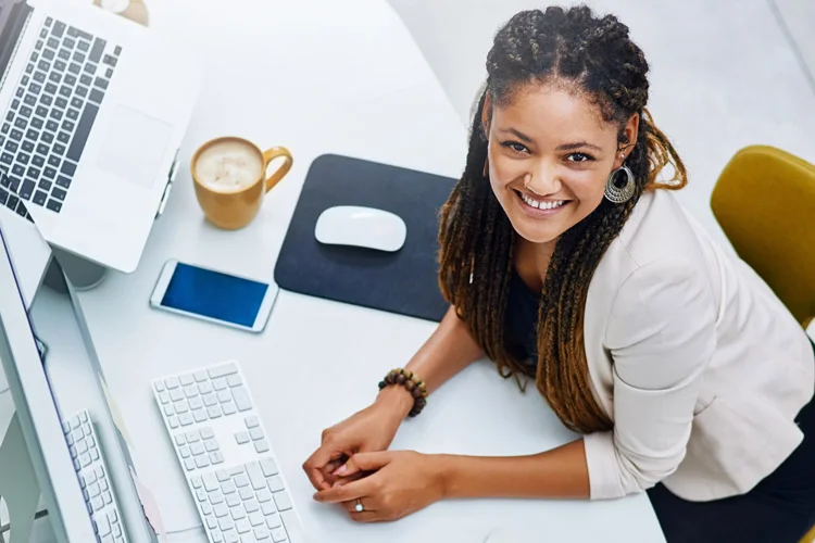 Jeune femme souriante les mains posées sur le bureau