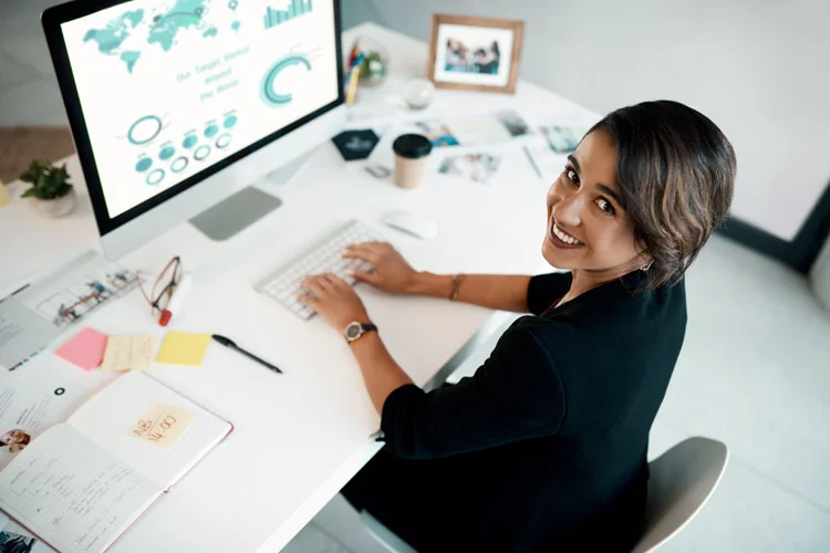 Jeune femme souriante tapant sur un ordinateur