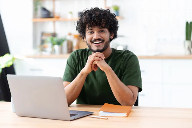 Homme devant son ordinateur portable avec un grand sourire